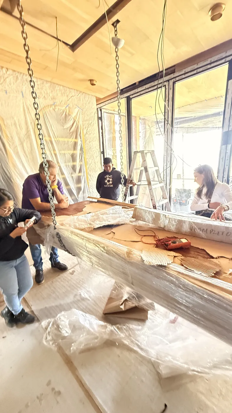Equipo revisando una pieza suspendida de cadenas en obra